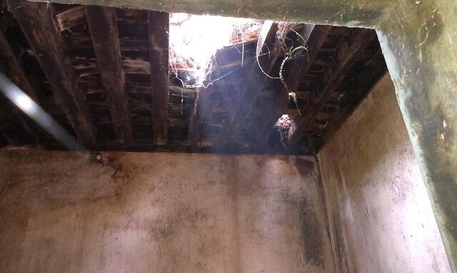 Shows picture of the roof of a dilapidated building with a big hole in it.