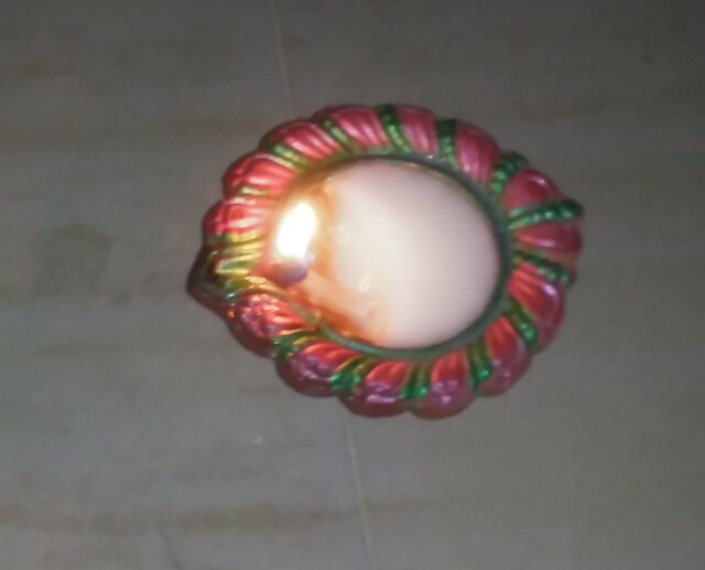 Shows an small oil lamp burning with solidified tallow in it.